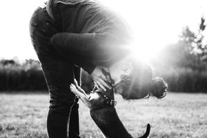 woman kissing dog with sunburst behind her