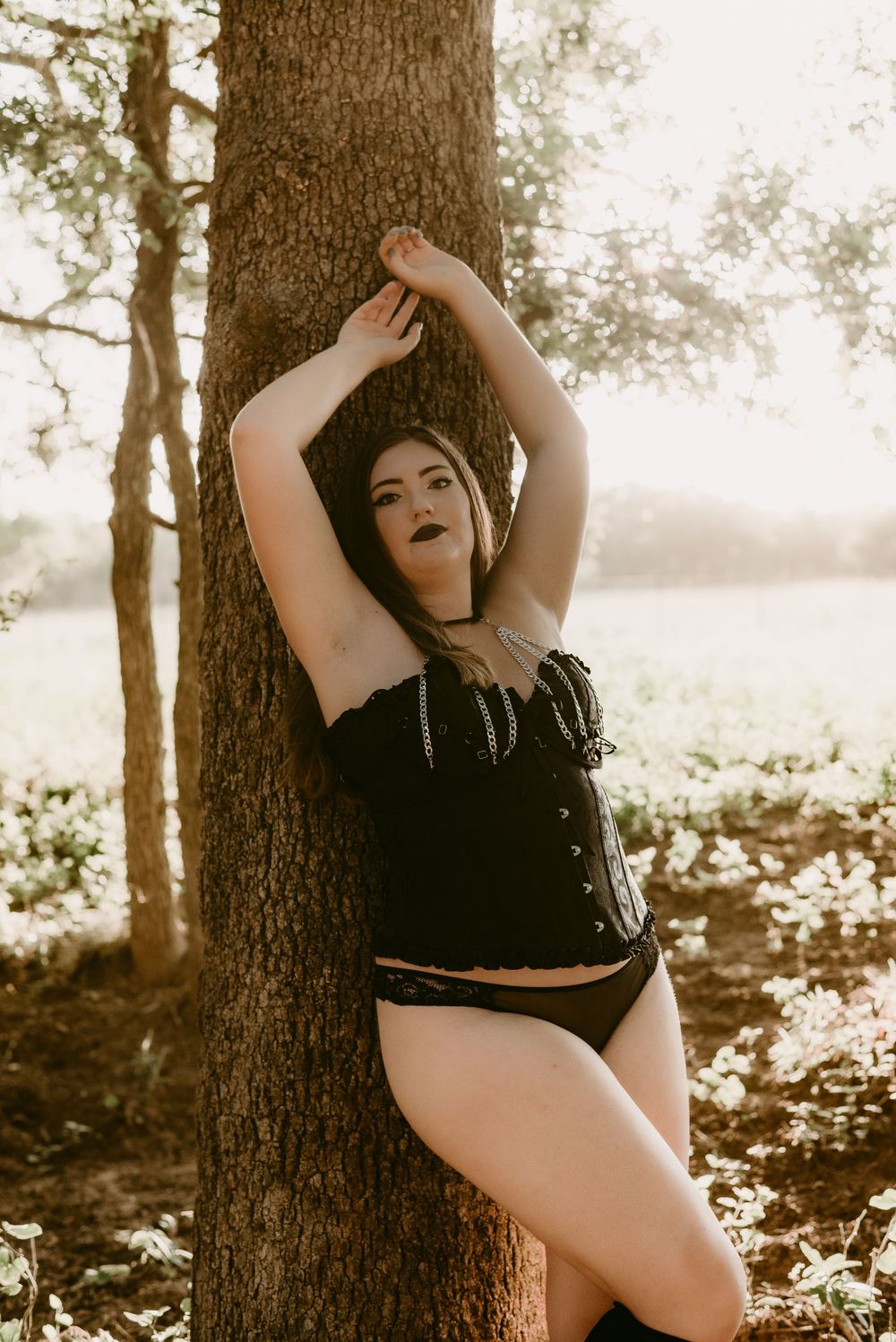 Ethereal boudoir photography with golden hour lighting in woodland setting.