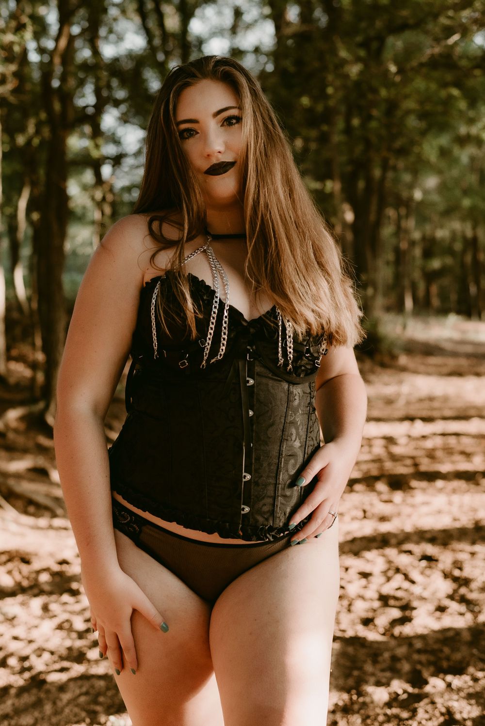 Fashion portrait in woodland setting featuring black corset and dramatic lighting.