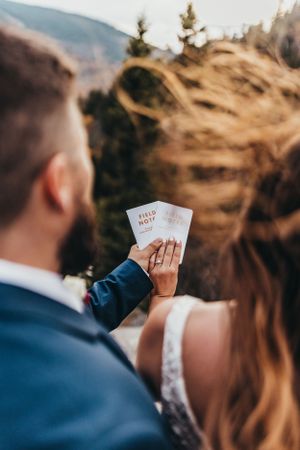 Wedding vow books held up against mountain landscape backdrop.