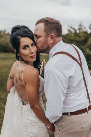 Intimate wedding portrait with couple in rustic attire against natural backdrop.