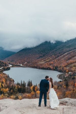 Mountain lake vista with fall foliage and misty peaks in background.