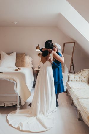 Wedding dress preparation scene in a bright white attic room.
