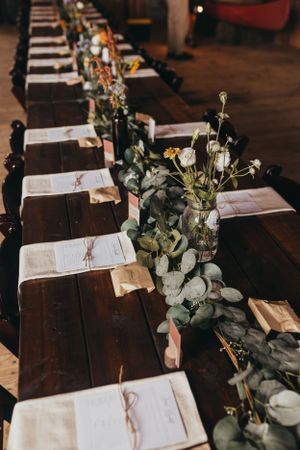 Rustic table settings with greenery garlands and open books at wedding reception.