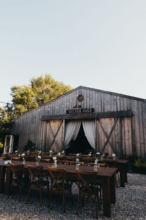 Rustic wooden barn venue with outdoor picnic tables and seating area for events.