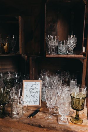 Collection of crystal glasses arranged on wooden shelves in vintage style.
