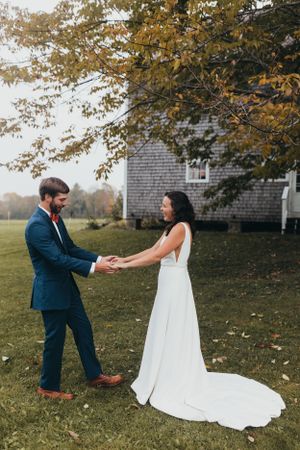 Wedding couple sharing a playful moment on autumn lawn with fall foliage.
