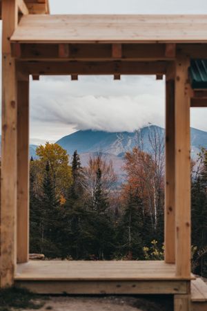 Mountain landscape viewed through wooden beams of a rustic structure in autumn.