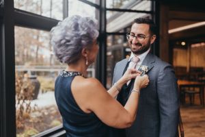 A touching moment as someone adjusts a boutonniere on a groom's lapel.