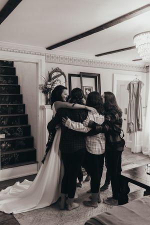 Black and white photo of emotional group hug during wedding preparations.