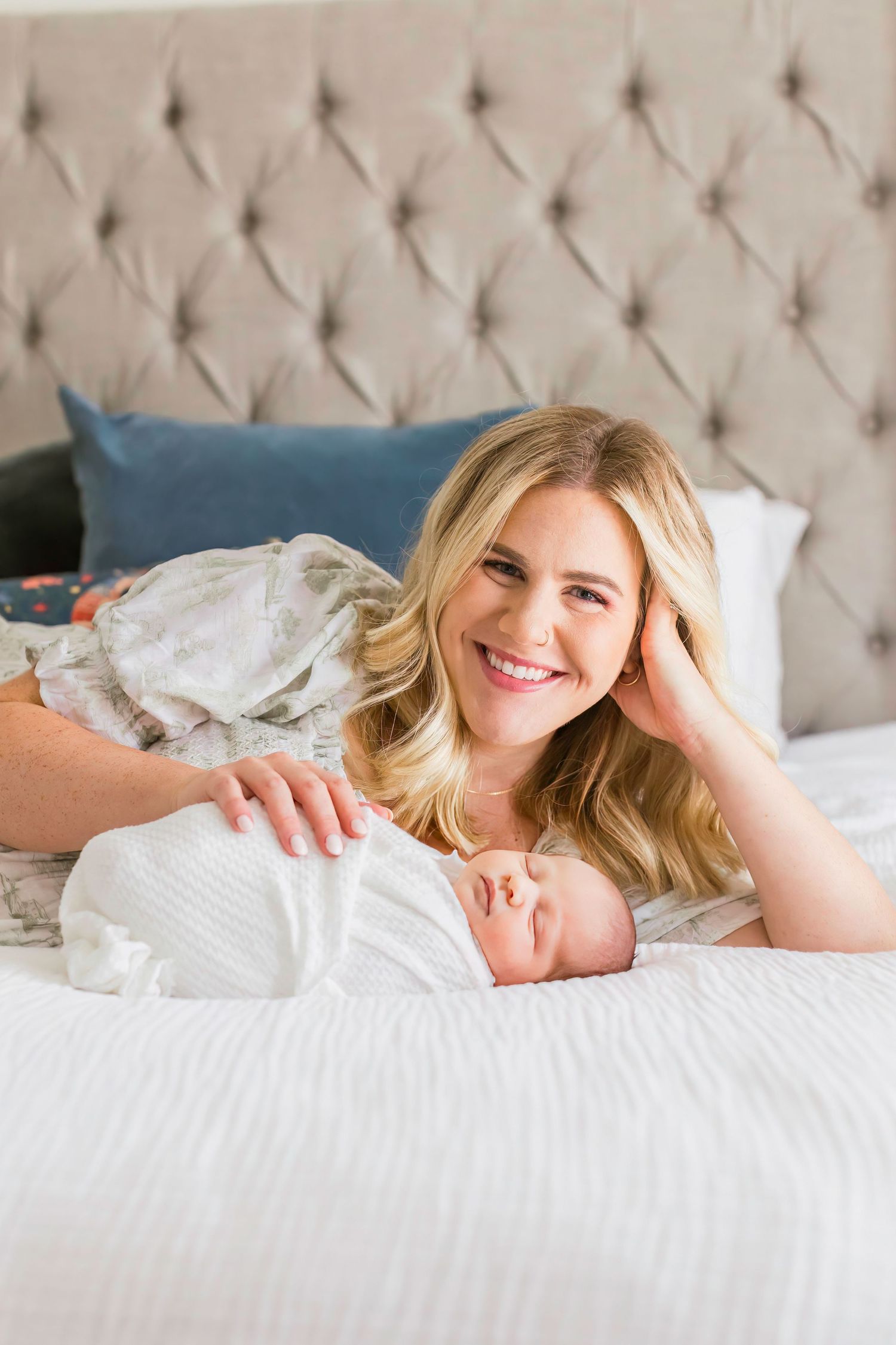 Mother and newborn sharing an intimate moment while resting on white bedding.