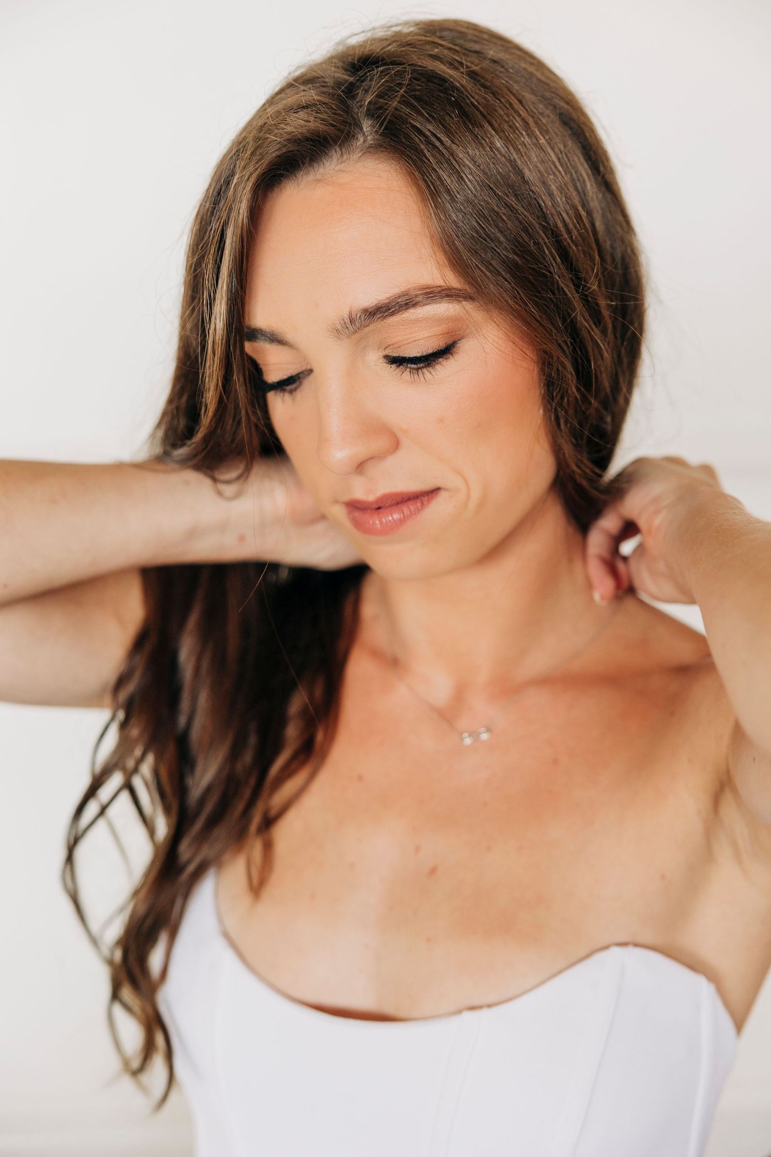 Bride putting on necklace before her wedding ceremony at The Ritz Carlton Beach Club by Sarasota wedding photographer.