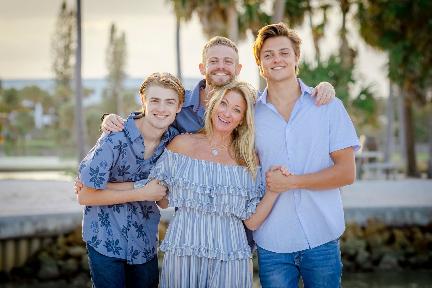 Family of four hugging and smiling by the water at Dubois Park in Jupiter, FL