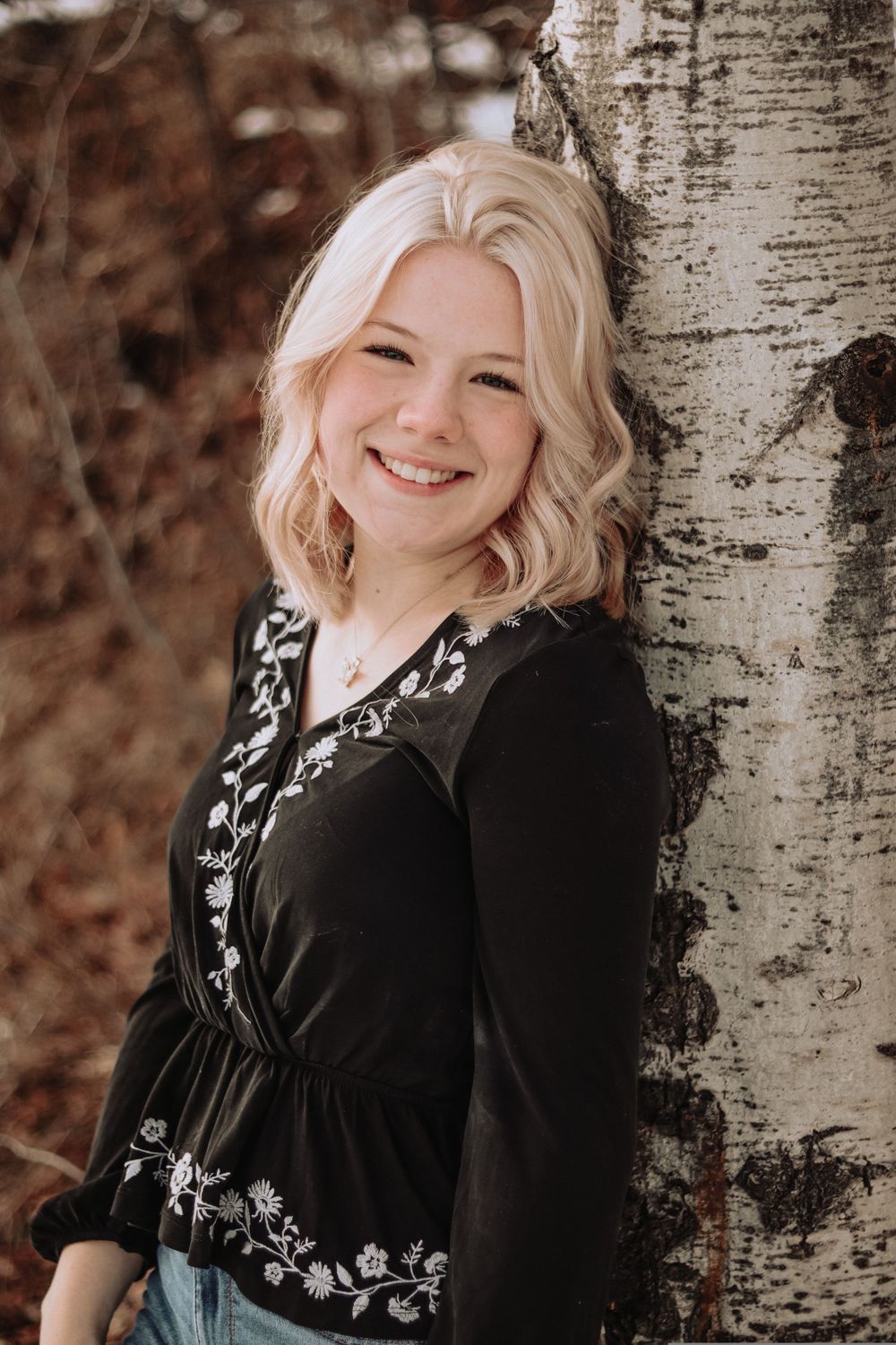 Portrait session against a birch tree trunk showing relaxed poses and natural expressions.