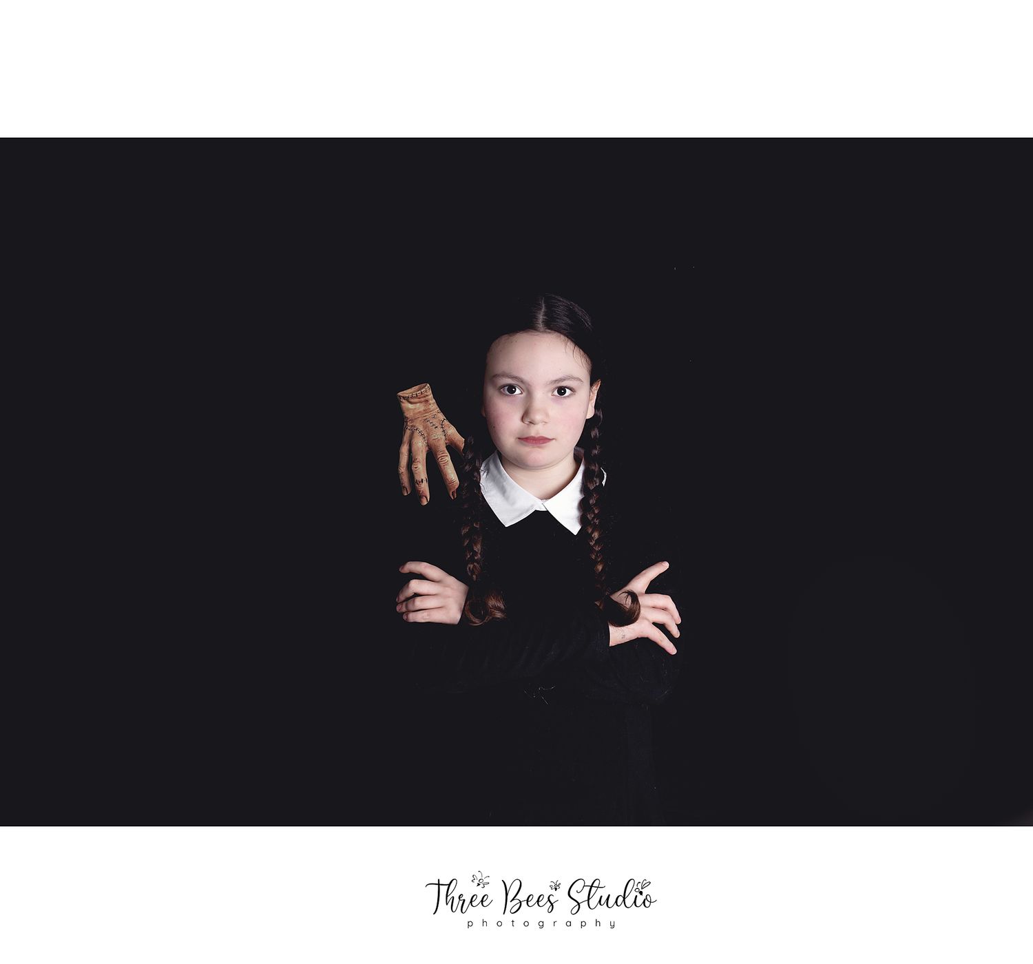Dramatic portrait with crossed arms and gothic styling against dark background.