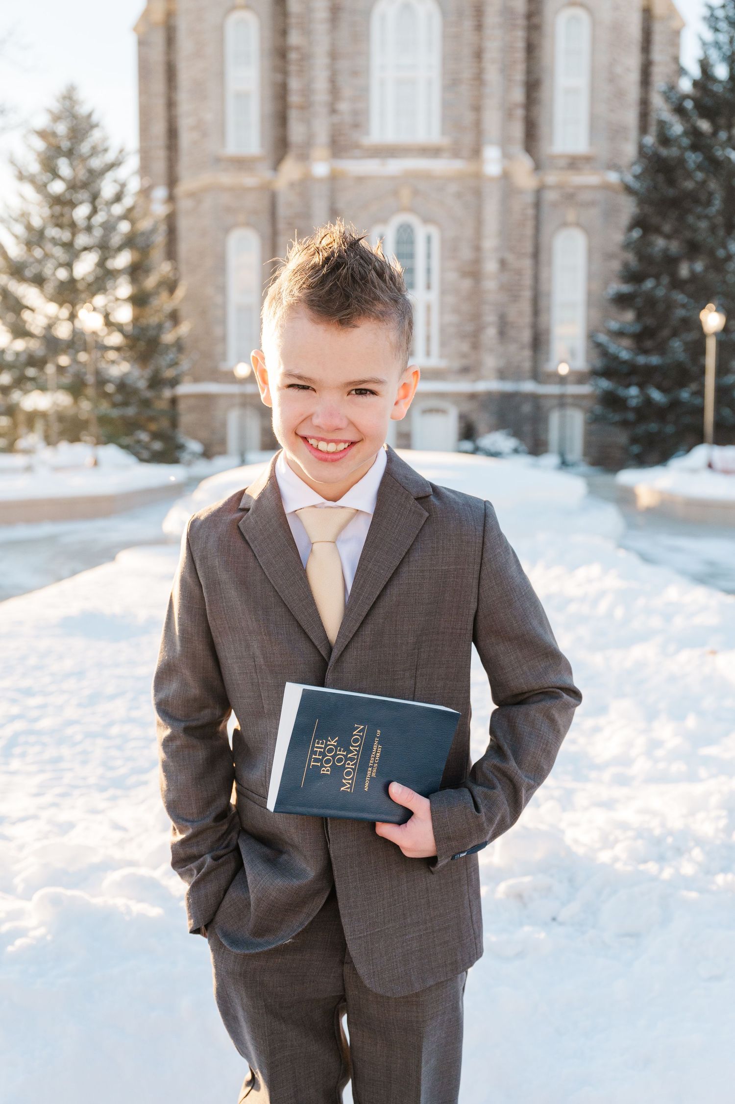 A person in a suit holds a book while standing in snowy winter scenery.