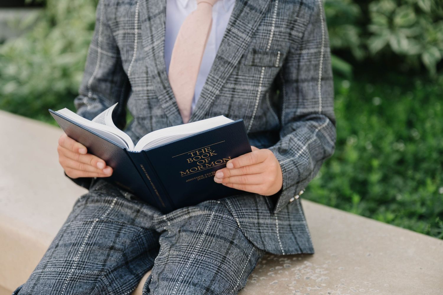 A close-up view of someone reading a book while wearing a grey checkered suit.