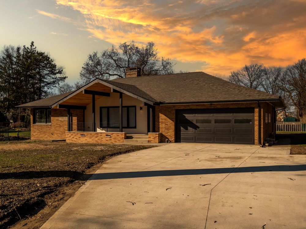 Ranch-style home with attached garage captured during a vibrant sunset with golden clouds.