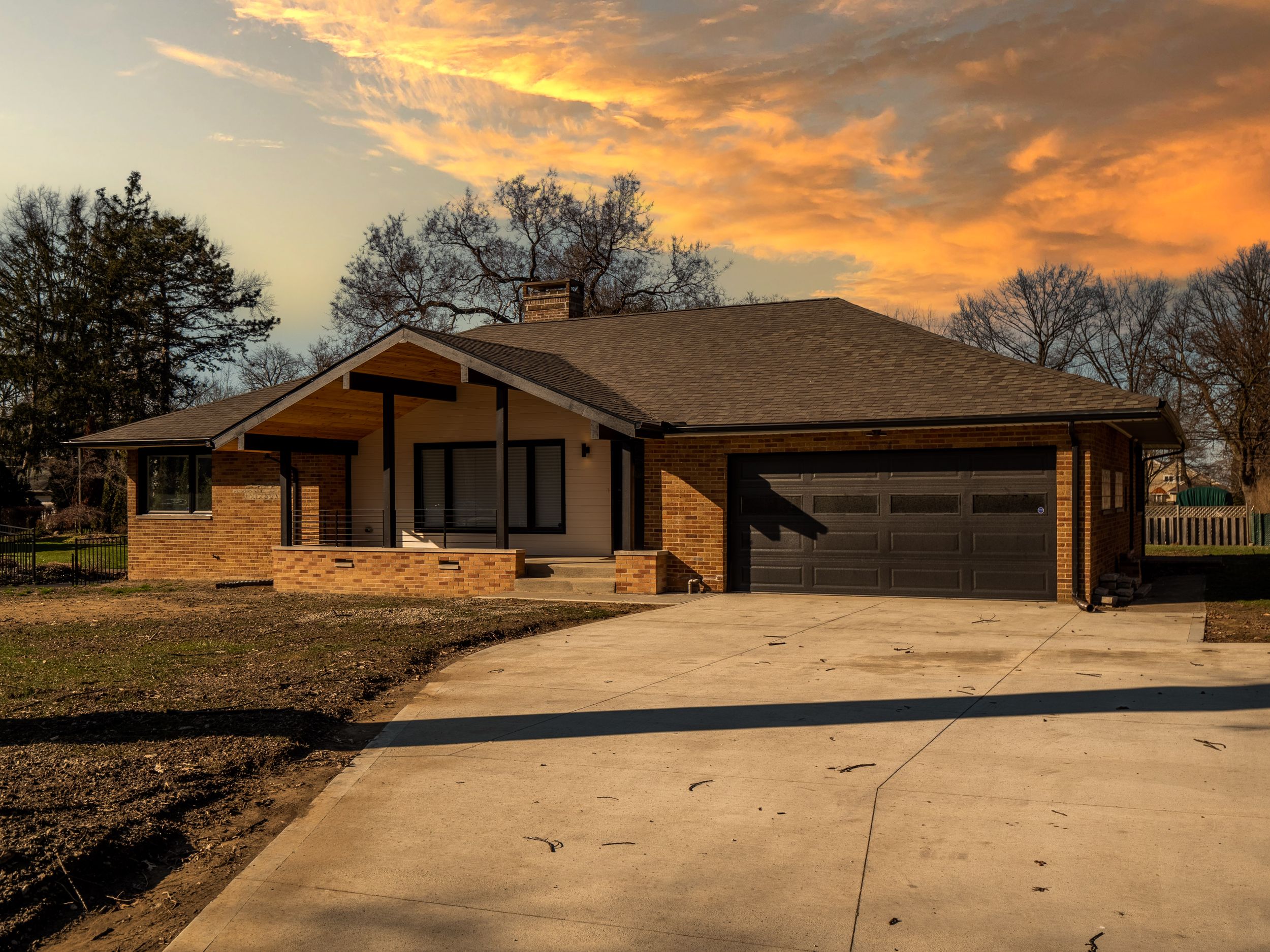Ranch-style home with attached garage captured during a vibrant sunset with golden clouds.
