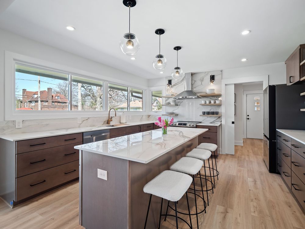 Sleek kitchen design with white countertops, bar seating, and large windows providing natural light.