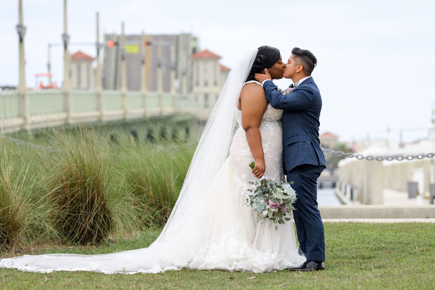 Romantic seaside wedding portrait with marina and buildings in background.