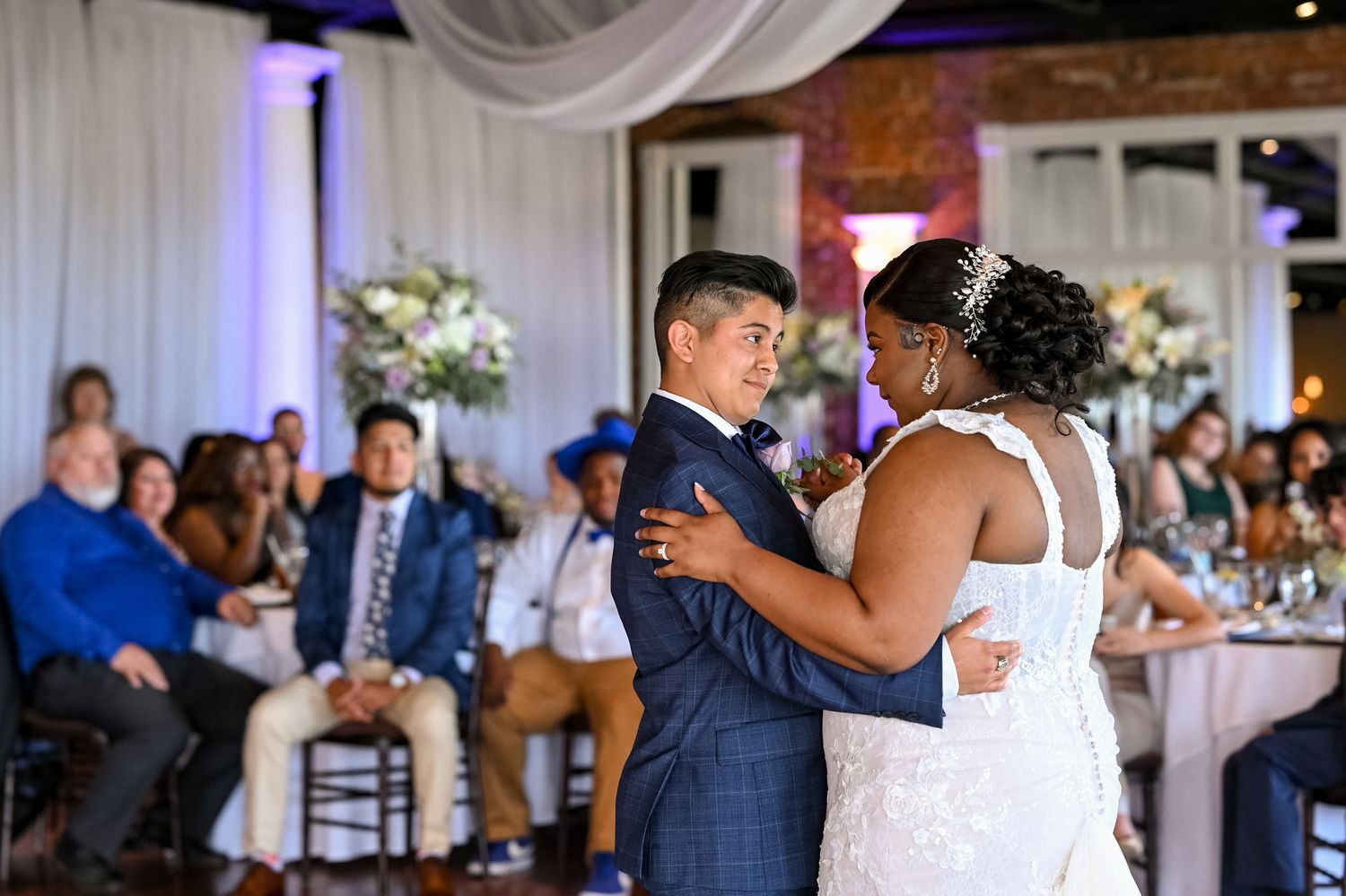 First dance at wedding reception with guests watching from decorated tables.