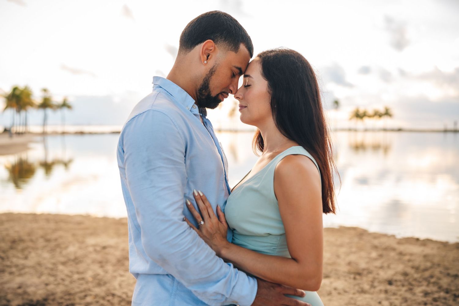 Intimate couple sharing a tender moment on a beach at sunset.