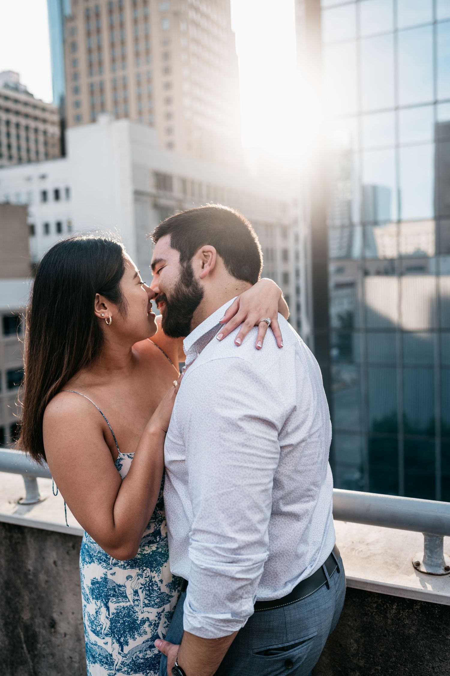 A romantic couple shares an intimate moment on a city rooftop at sunset.