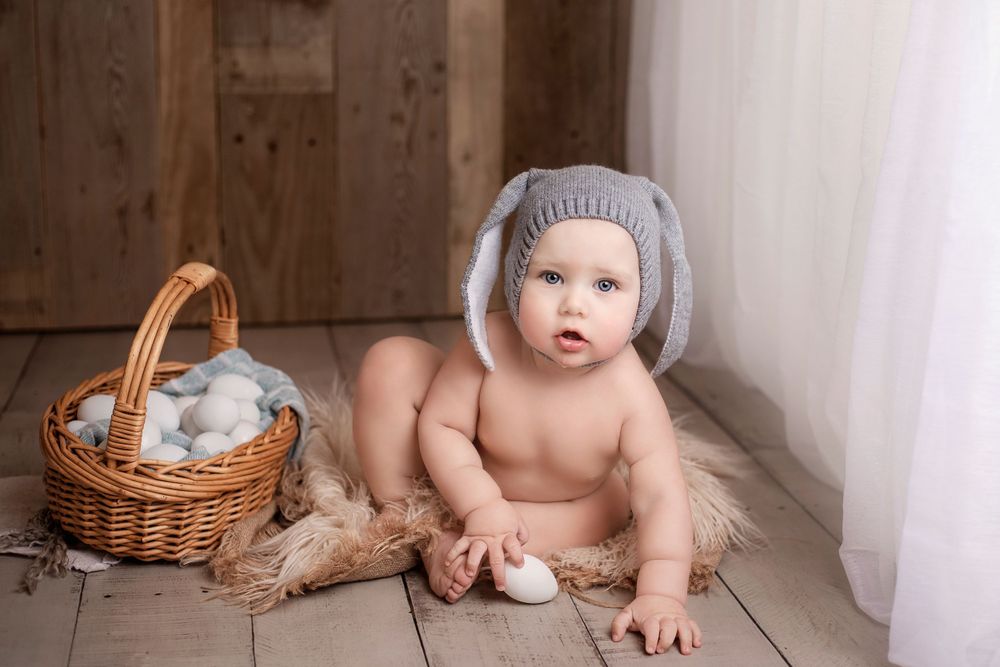 Baby sitting next to easter egg basket and wearing knit bunny hat.  Wisconsin Baby Portrait