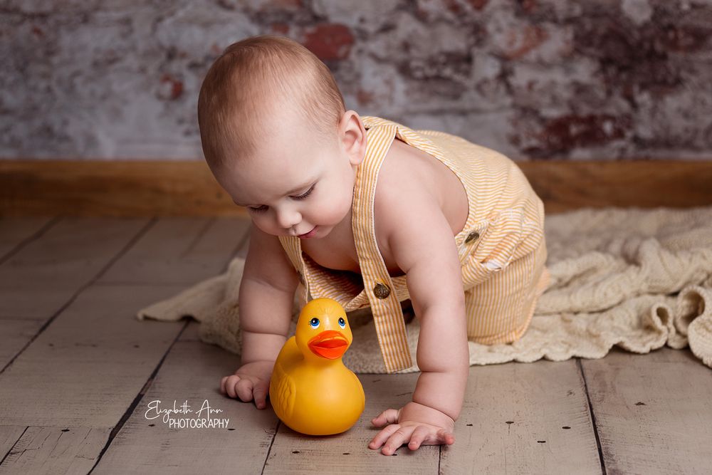 Crawling baby boy wearing vintage overalls with vintage rubber ducky, brick wall.  Wisconsin Baby Portrait