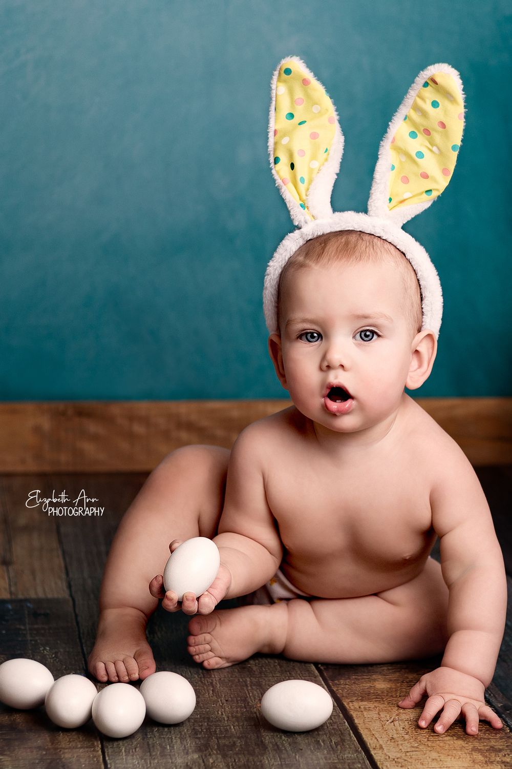 Easter portrait of baby wearing bunny ears and holding an egg.  Wisconsin Baby Portrait