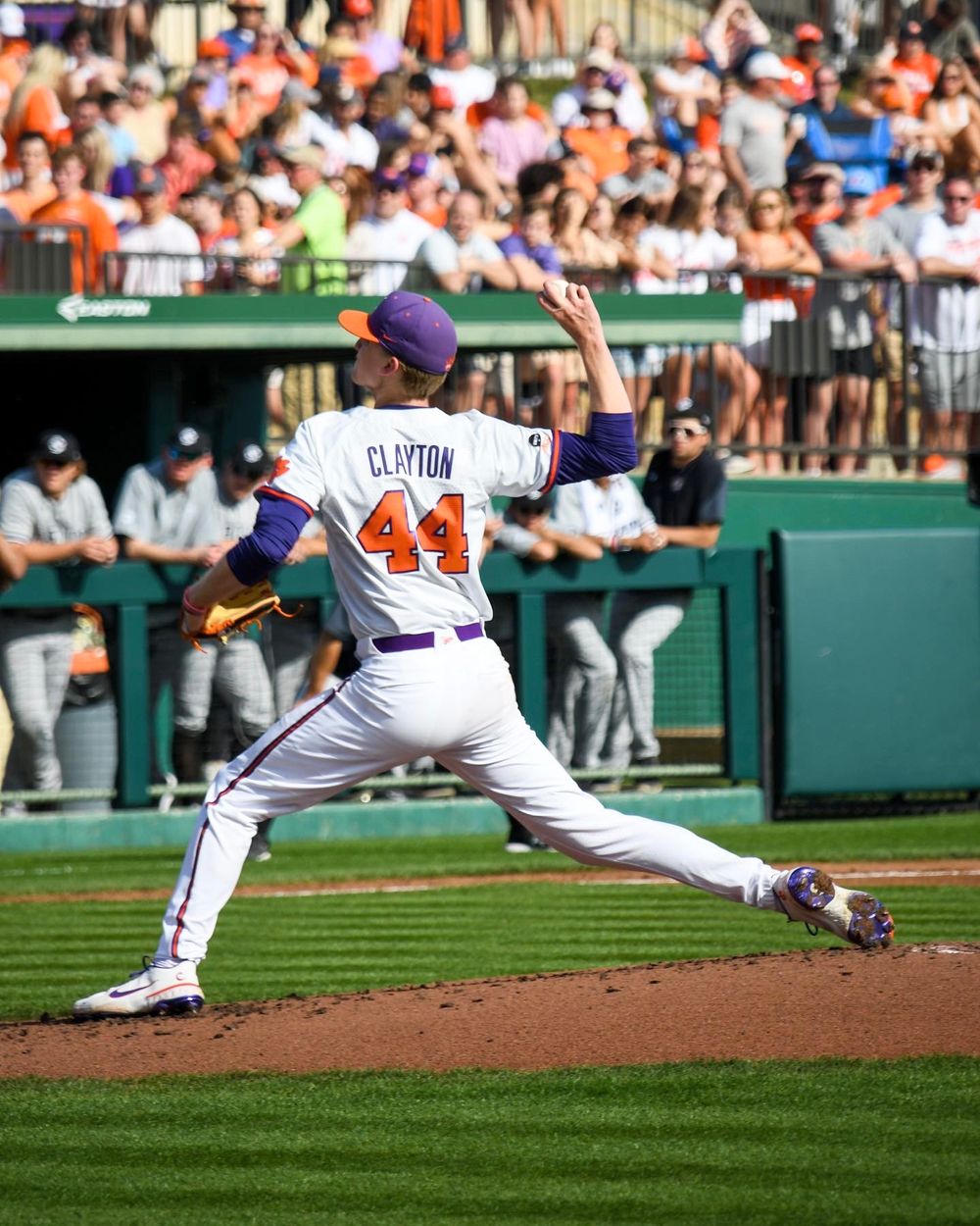 Baseball pitcher in motion delivers a pitch during a sunny afternoon game.