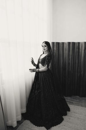 Black and white portrait of a traditional bridal outfit with dramatic lighting and curtained backdrop.
