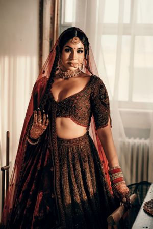 Close-up shot of traditional bridal jewelry and embroidered lehenga with red dupatta.