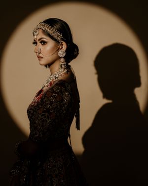 Traditional South Asian bridal fashion with intricate jewelry and embroidered outfit against sepia backdrop.