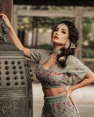 Model in grey floral lehenga poses dramatically against vintage mailbox.