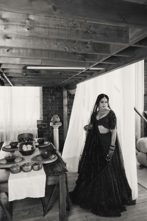 Black and white photograph of traditional bridal attire beside rustic table settings.