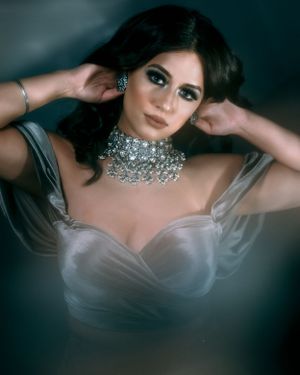 Model wearing crystal choker and silver corset top poses in glamorous portrait.