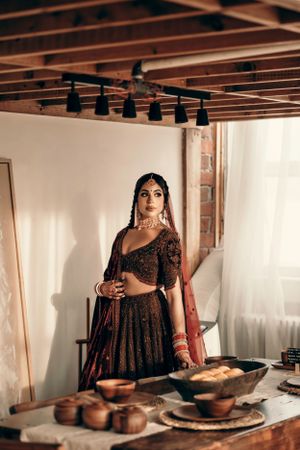Traditional bridal attire photographed in rustic setting with wooden ceiling beams and table settings.