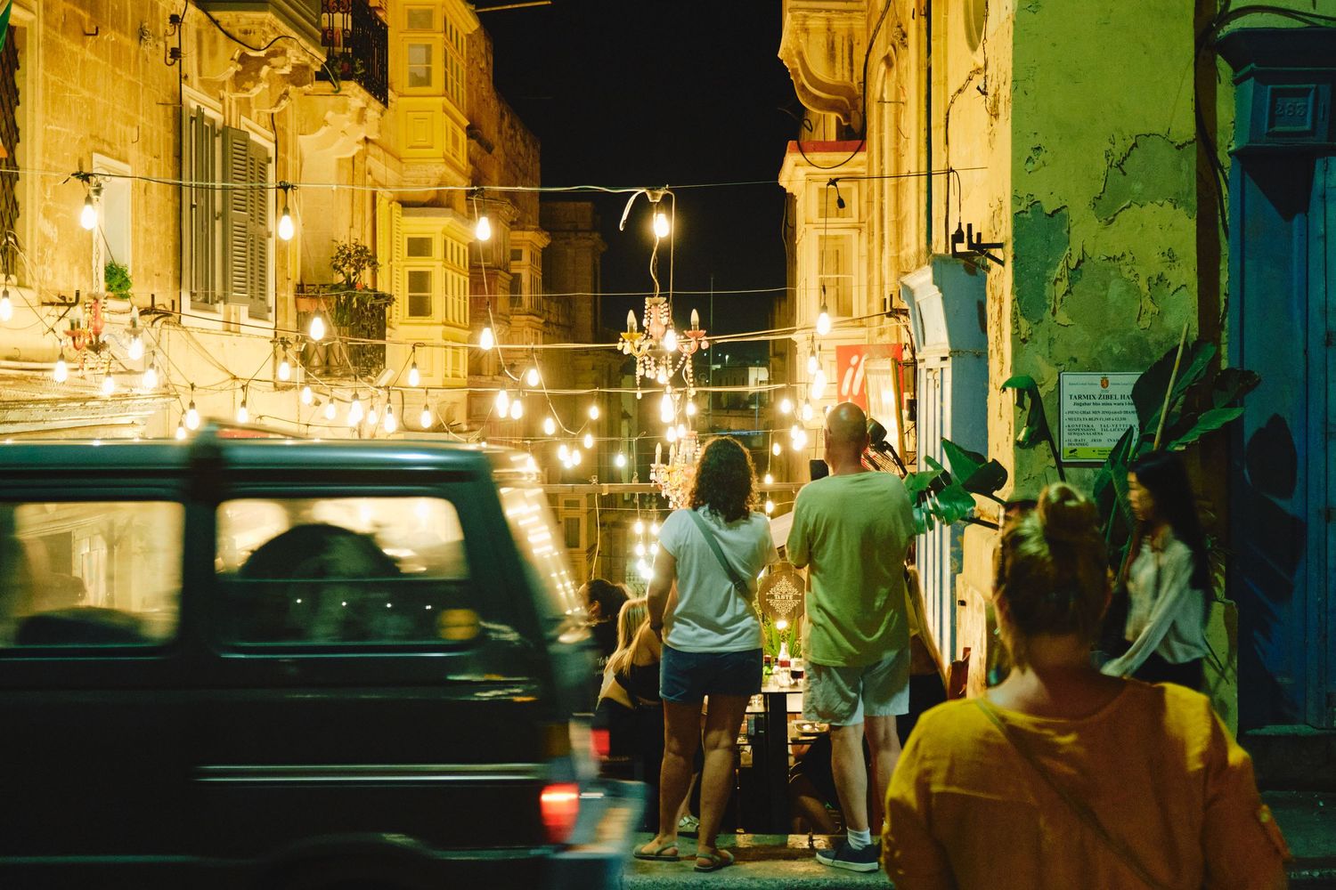 Nighttime street scene with string lights and buildings illuminated in warm glow.