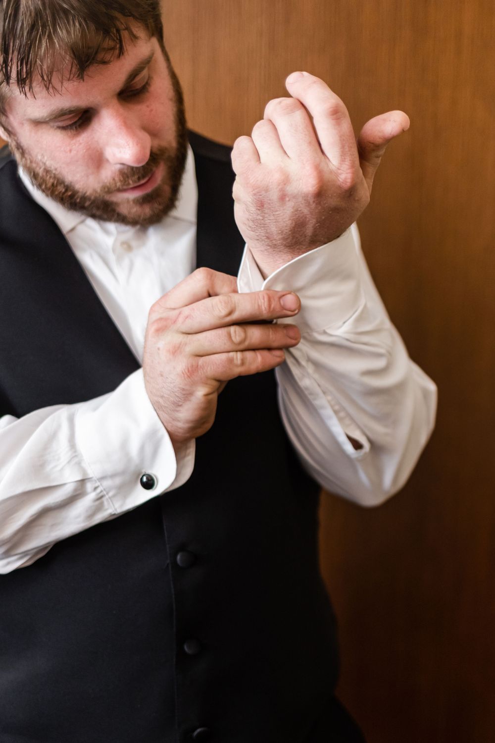 Person in formal attire adjusting white shirt cuff buttons.