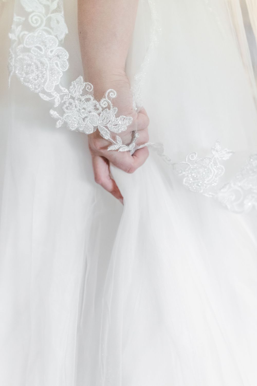 Close-up of delicate lace details on white wedding dress fabric.