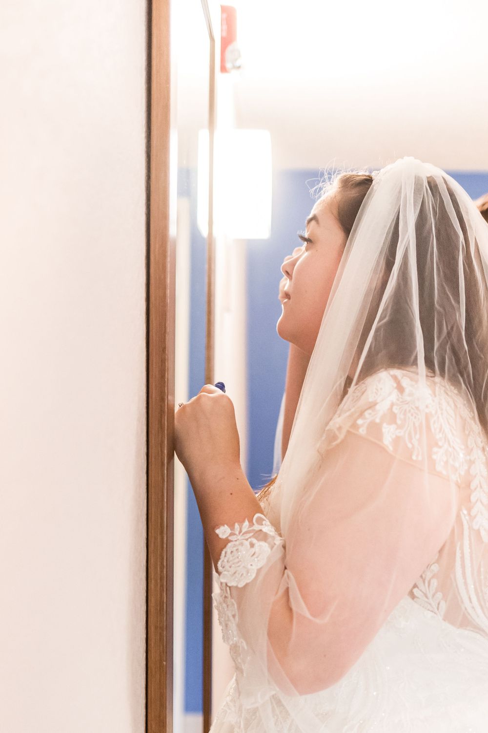 A bride in a delicate lace wedding gown and veil prepares for her special day.