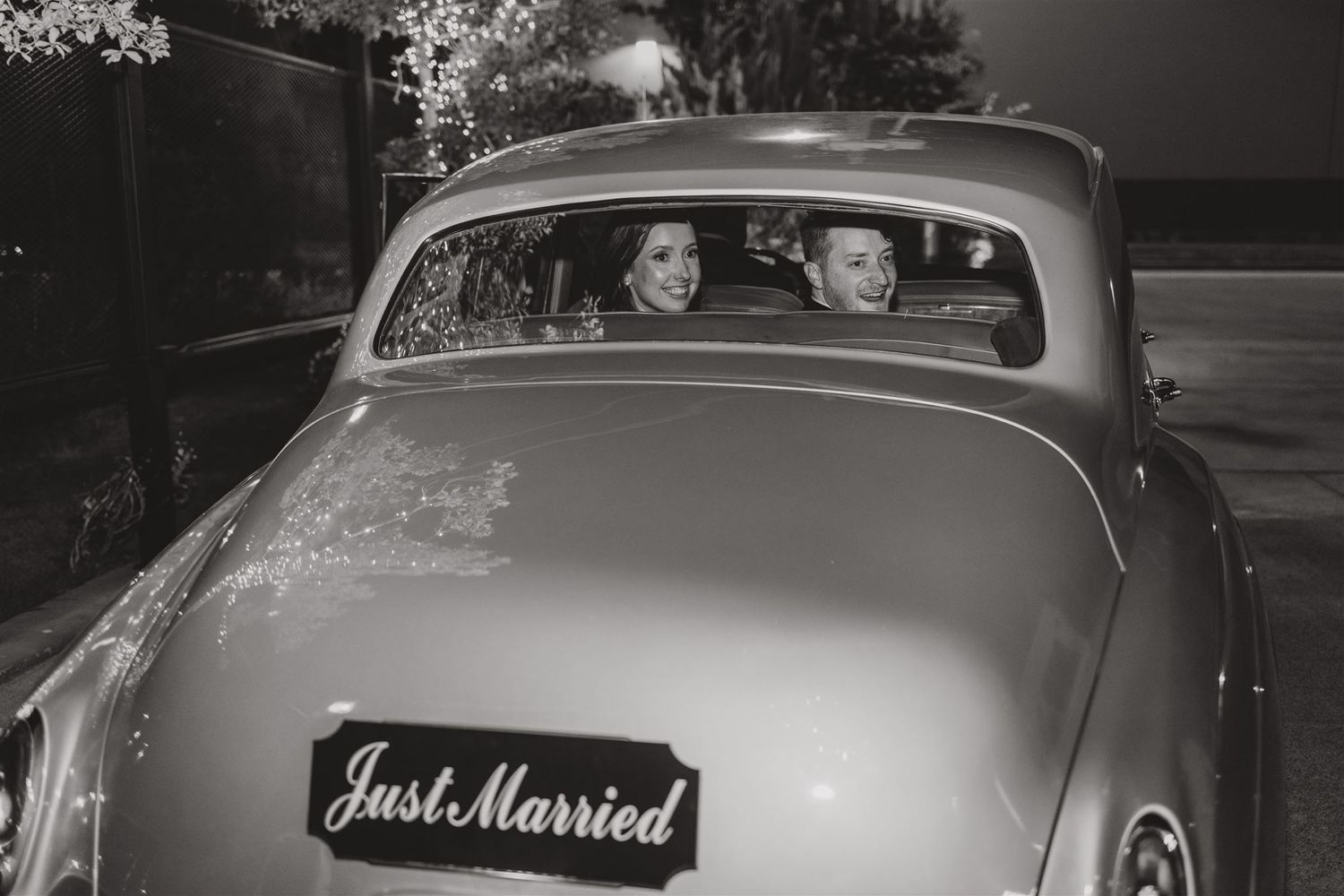 Vintage black and white photo of a classic car with 'Just Married' sign on the back.