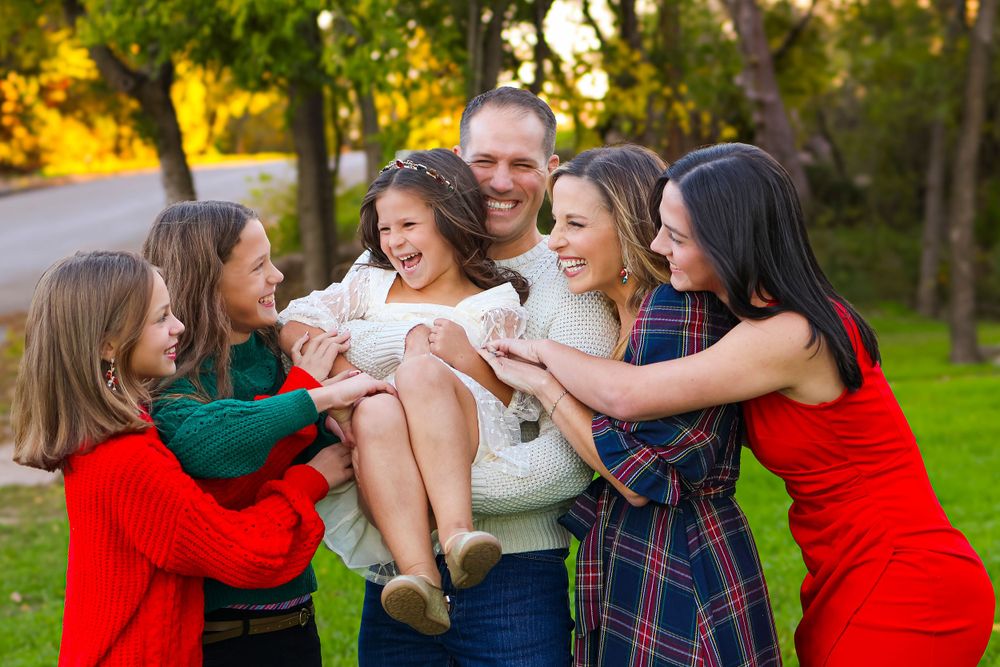 A cheerful family moment captured outdoors with playful interactions in a park setting.
