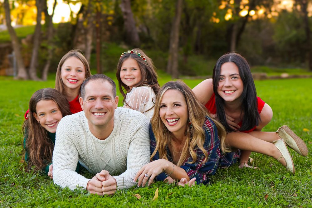 A happy family lying together on green grass during a sunset outdoor photo session.