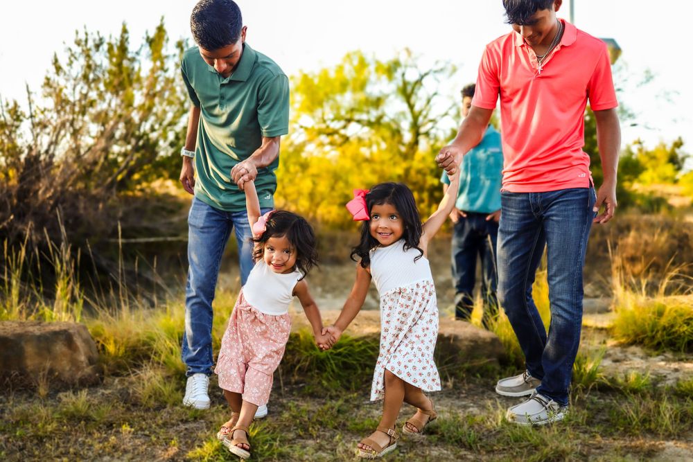 Family enjoying a playful walk together in a natural outdoor setting during golden hour.