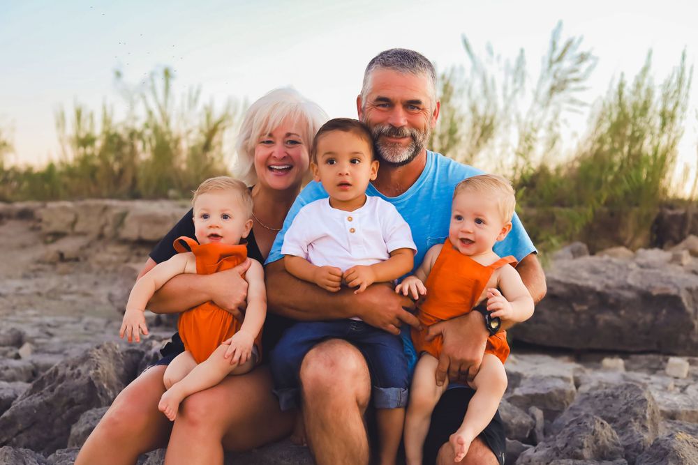 A family portrait on rocky terrain during golden hour showing multiple generations together outdoors.