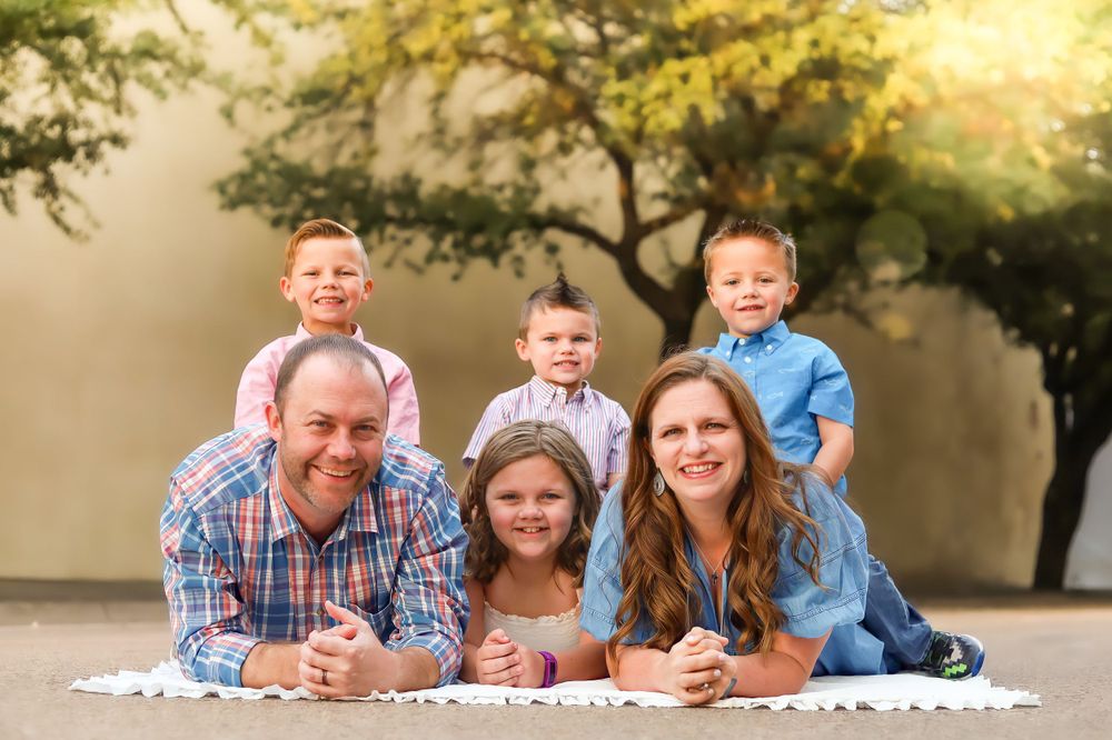 Family portrait with everyone lying on ground outdoors during golden hour.