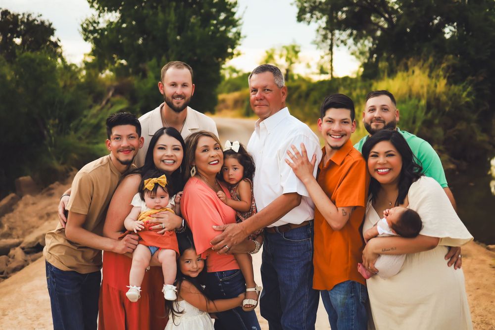 Extended family gathering outdoors for group portrait at sunset.